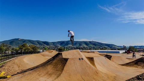 Boy riding bike jumping over hill.