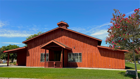 Red barn with grass and blue skies.